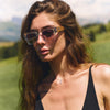 Woman wearing sunglasses and a black top in a natural setting