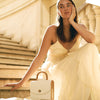 Model in a light dress on stone steps with the BLACKWOOD Aurora White Saffiano handbag